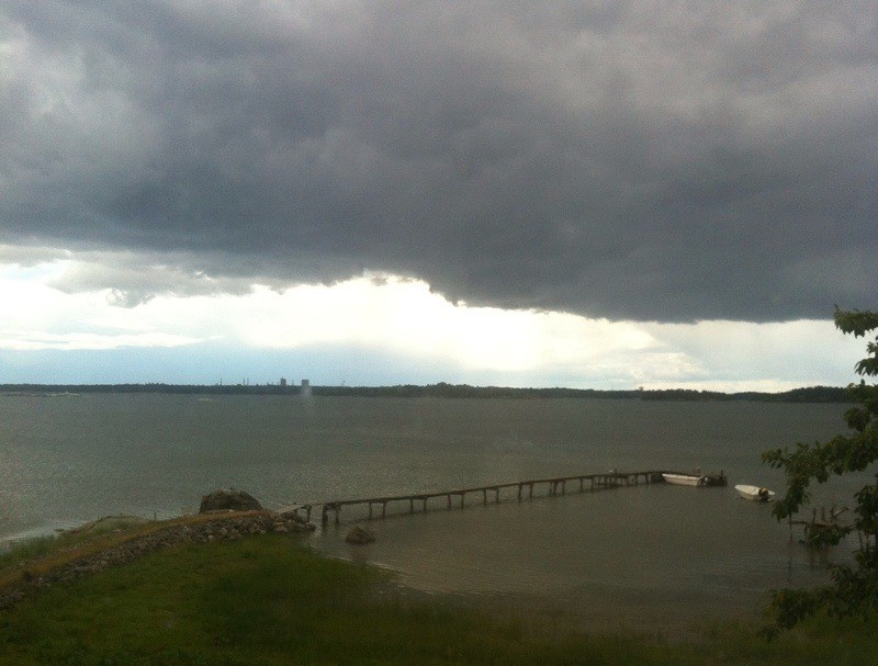 Utsikt vid hav och brygga på lantstället, mörka moln
