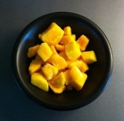 Mango i en svart skål. Skafferiet är inte en plats för fryst mango...